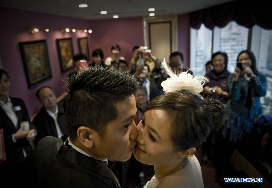 A groom kisses his bride at their wedding in Hong Kong, south China, Dec. 12, 2012. A total of 696 couples flocked to tie the knot on Dec. 12, 2012, or 12/12/12, which sounds like "will love/will love/will love" in Chinese. (Xinhua/Lui Siu Wai)