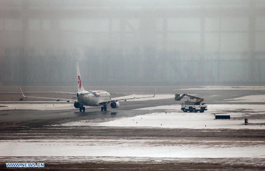 Ground crew members remove snow for a passenger plane at Beijing Capital International Airport in Beijing, capital of China, Dec. 12, 2012. A snow that hit China's capital city on Wednesday has led to massive flight delays at Beijing Capital International Airport. (Xinhua/Wan Xiang) 