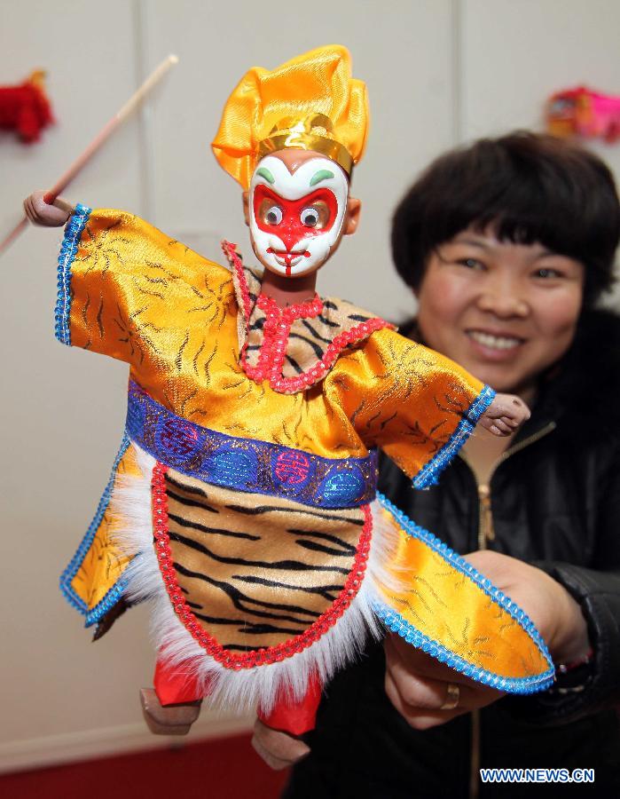 A staff member of Fujian pavilion demonstrates a doll during the 2012 China Time-Honoured Brand Expo in Beijing, capital of China, Dec. 12, 2012. The five-day expo, opening Wednesday at the Beijing Exhibition Center, attracted some 160 Chinese time-honoured brand exhibitors. (Xinhua)