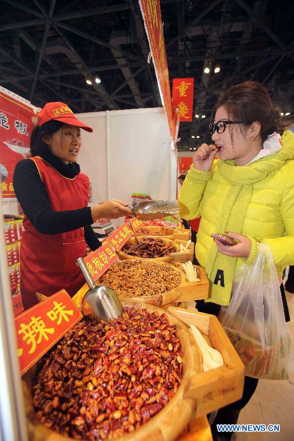 A visitor tries spicy snacks at Chongqing pavilion during the 2012 China Time-Honoured Brand Expo in Beijing, capital of China, Dec. 12, 2012. The five-day expo, opening Wednesday at the Beijing Exhibition Center, attracted some 160 Chinese time-honoured brand exhibitors. (Xinhua)