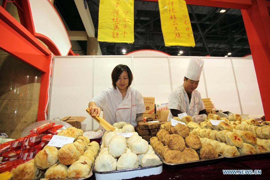 Staff members of Tianjin pavilion make traditional "huoshao" pastries during the 2012 China Time-Honoured Brand Expo in Beijing, capital of China, Dec. 12, 2012. The five-day expo, opening Wednesday at the Beijing Exhibition Center, attracted some 160 Chinese time-honoured brand exhibitors. (Xinhua)