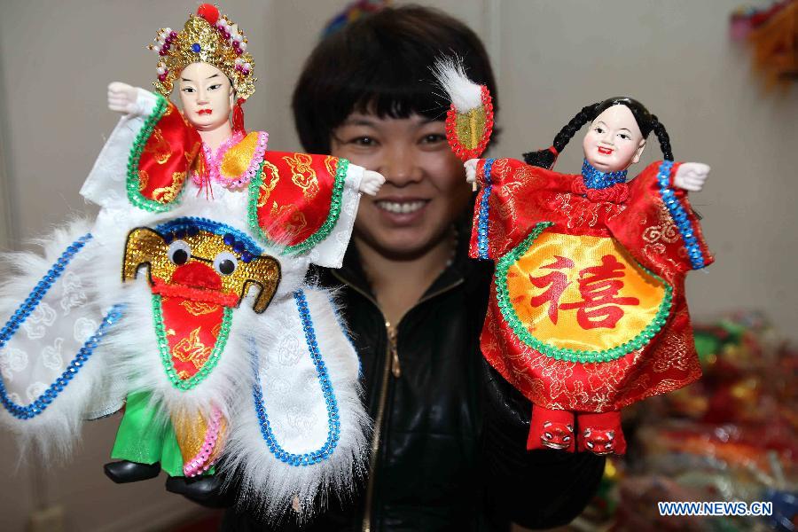 A staff member of Fujian pavilion demonstrates two dolls during the 2012 China Time-Honoured Brand Expo in Beijing, capital of China, Dec. 12, 2012. The five-day expo, opening Wednesday at the Beijing Exhibition Center, attracted some 160 Chinese time-honoured brand exhibitors. (Xinhua)