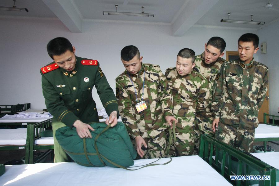 A veteran (L) teaches Newly recruited para-military policemen packing a quilt in Hohhot, north China's Inner Mongolia Autonomous Region, Dec. 12, 2012. Newly recruited soldiers of People's Liberation Army (PLA) and para-military policemen joined their units around the country recently. (Xinhua/Zhang Fan)