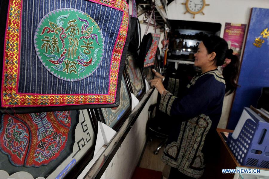 Wei Taohua, a horse-tail embroidery craftswoman of Shui ethnic group, aligns finished horsetail embroidery works in Sandu, southwest China's Guizhou Province, Dec. 12, 2012. (Xinhua/Ou Dongqu)