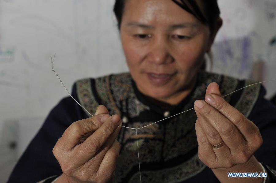 Wei Taohua, horse-tail embroidery craftswoman of Shui ethnic group, wraps horsetail hairs with a thread in Sandu, southwest China's Guizhou Province, Dec. 12, 2012. (Xinhua/Ou Dongqu)