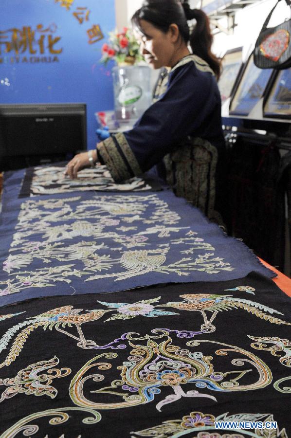 Wei Taohua, a horse-tail embroidery craftswoman of Shui ethnic group, checks finished horsetail embroidery works in Sandu, southwest China's Guizhou Province, Dec. 12, 2012. (Xinhua/Ou Dongqu)