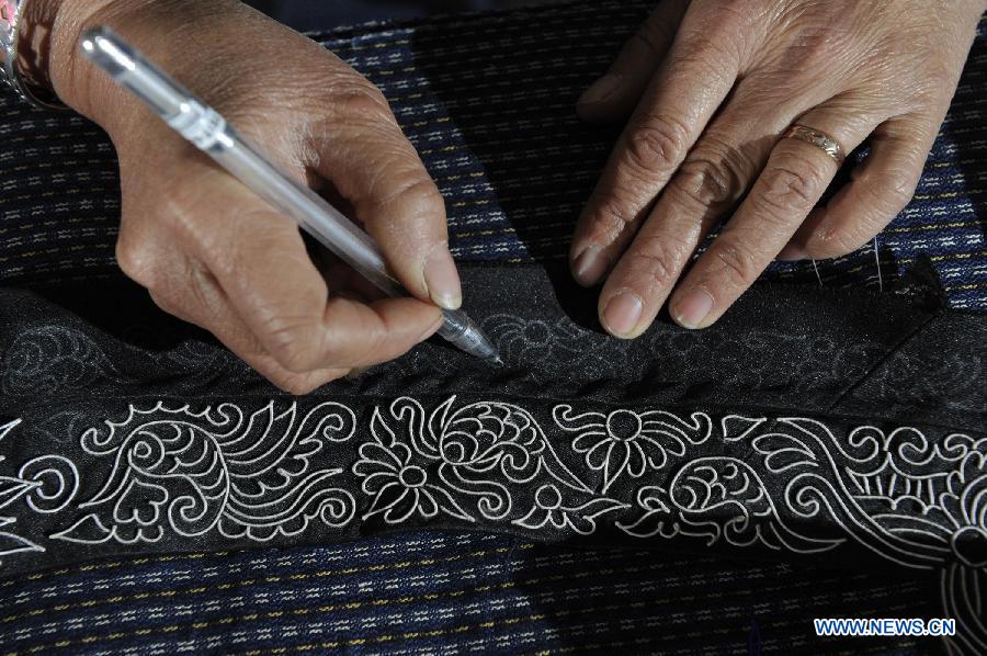 Wei Taohua, a horse-tail embroidery craftswoman of Shui ethnic group, designs embroidery patterns in Sandu, southwest China's Guizhou Province, Dec. 12, 2012. (Xinhua/Ou Dongqu)