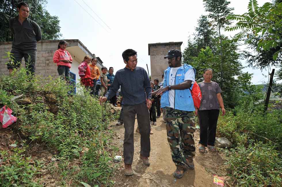 Diarra Boubacar checks a foot of villager Chen Degang whose foot has strained in Boyi Village, Luozehe Town, Yiliang County, southwest China's Yunnan Province, Sept. 15, 2012.(Xinhua/Li Xin)
