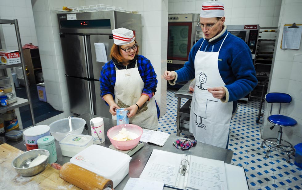 Uwe Brutzer (R) communicates with his Chinese student Jin Jing, a deaf-mute girl, at the "Bach's Bakery" in Changsha, capital of central China's Hunan Province, Feb. 8, 2012.(Xinhua/Bai Yu)