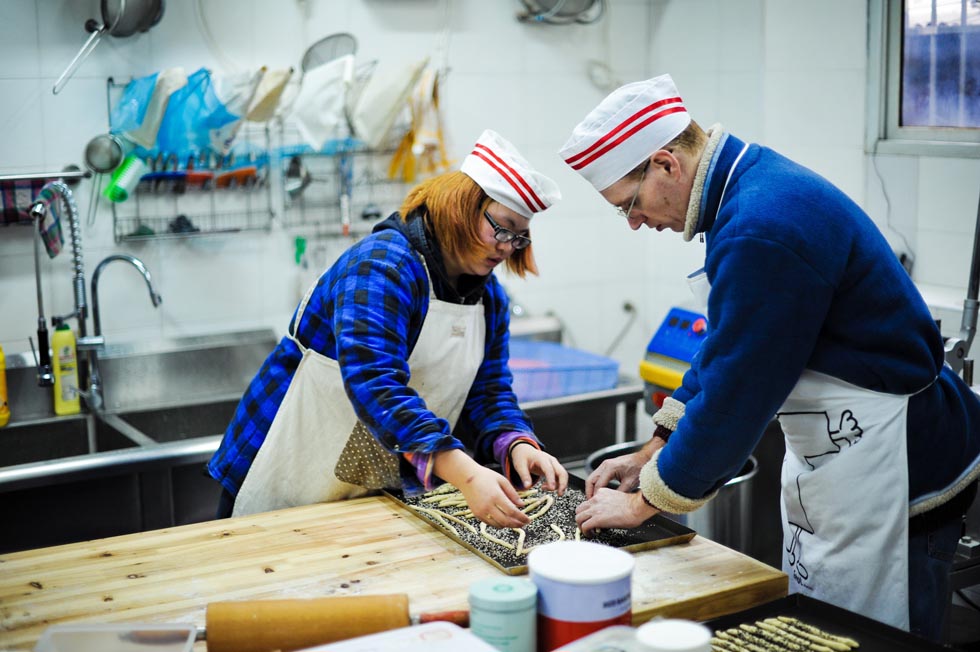 Uwe Brutzer (R) and his Chinese student Jin Jing, a deaf-mute girl, make cookies at the "Bach's Bakery" in Changsha, capital of central China's Hunan Province, Feb. 8, 2012.(Xinhua/Bai Yu)