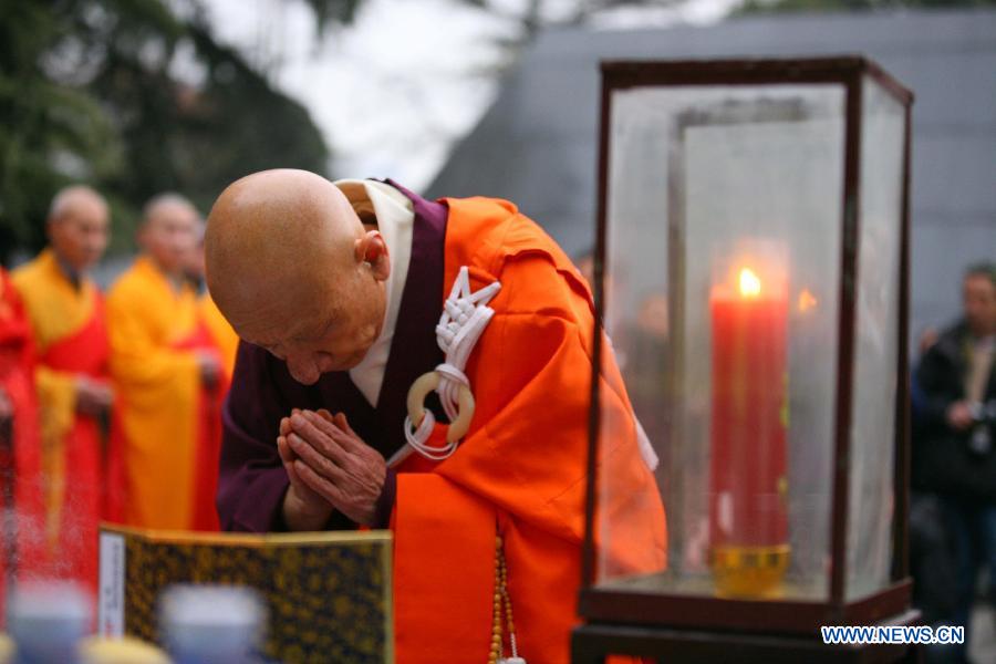 A Japanese monk prays in front of a memorial wall on which names of the Nanjing Massacre victims are engraved, during a religious service at the Memorial Hall of the Victims in Nanjing Massacre by Japanese Invaders in Nanjing, capital of east China's Jiangsu Province, Dec. 13, 2012, to mark the 75th anniversary of the Nanjing Massacre.(Xinhua)