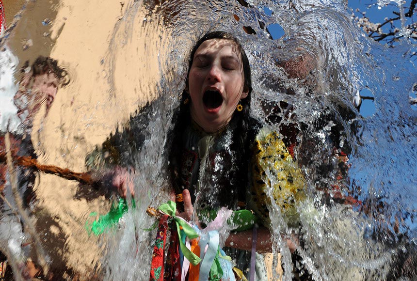 A youth wearing traditional costume splashes water on a girl in celebration of Easter in a village in Slovakia on April 19, 2012. (AFP/Samuel Kubani)