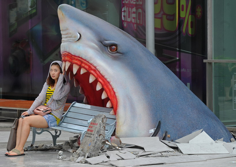 A tourist sitting beside the figure of “Shark’s Mouth” poses for photo in Thailand on July 9, 2012. Due to the political chaos, Thailand as “smile place” faces to challenge. (Photo/AFP)
