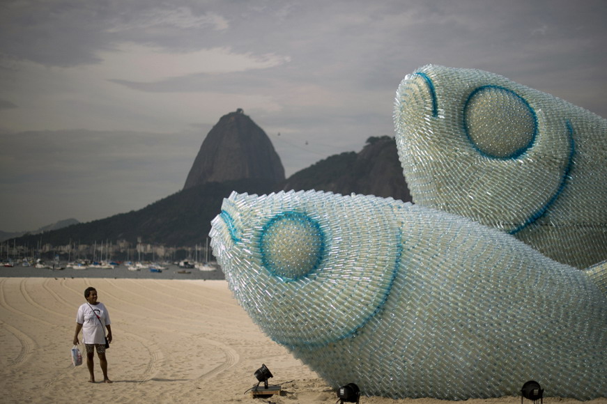 A lady views a fish-shaped artistic work made of recycled bottles at Botafogo beach in Rio de Janeiro, Brazil on June 19, 2012. (Photo/AFP)