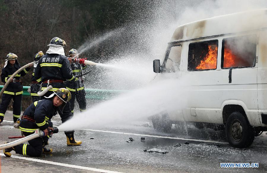 Firefighters put out a fire in the simulated accident vehicle during the 2012 highway traffic emergency drill in Yingshan County, central China's Hubei Province, Dec. 13, 2012. The drill held on Thursday involved over 800 personnel from armed police, fire control, medical rescue and other departments. (Xinhua/Wan Xiang)