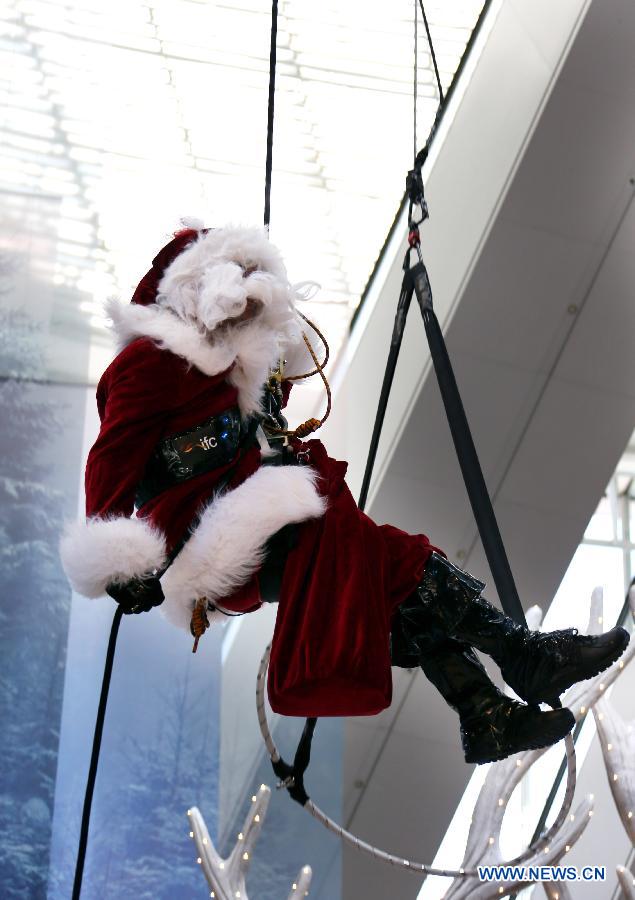 A Santa Claus impersonator from Australia performs at the International Finance Center Mall in Hong Kong, south China, Dec. 13, 2012. A group of Autralian actors and actresses were invited to present 30 shows which combined stunts and dances in the mall from Thursday until Dec. 26, 2012. (Xinhua/Li Peng)