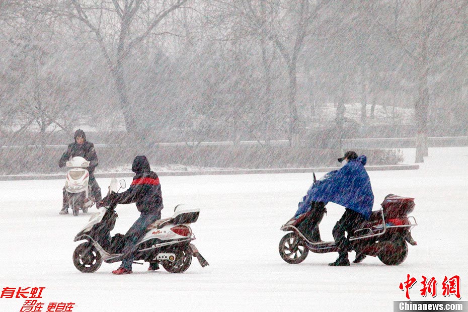 People drive motorcycles on a snow-covered street in Taiyuan, capital of north China's Shanxi Province, Dec. 13, 2012. Heavy snow battered parts of northern China on Thursday. (Photo/Chinanews.com)