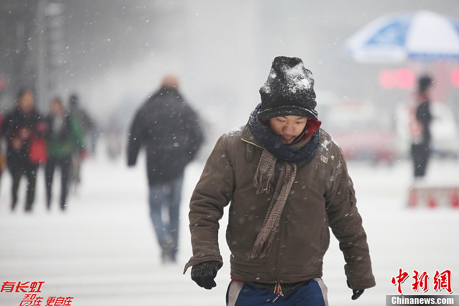 Residents walk on a snow-covered street in Taiyuan, capital of north China's Shanxi Province, Dec. 13, 2012. Heavy snow battered parts of northern China on Thursday.(Photo/Chinanews.com)