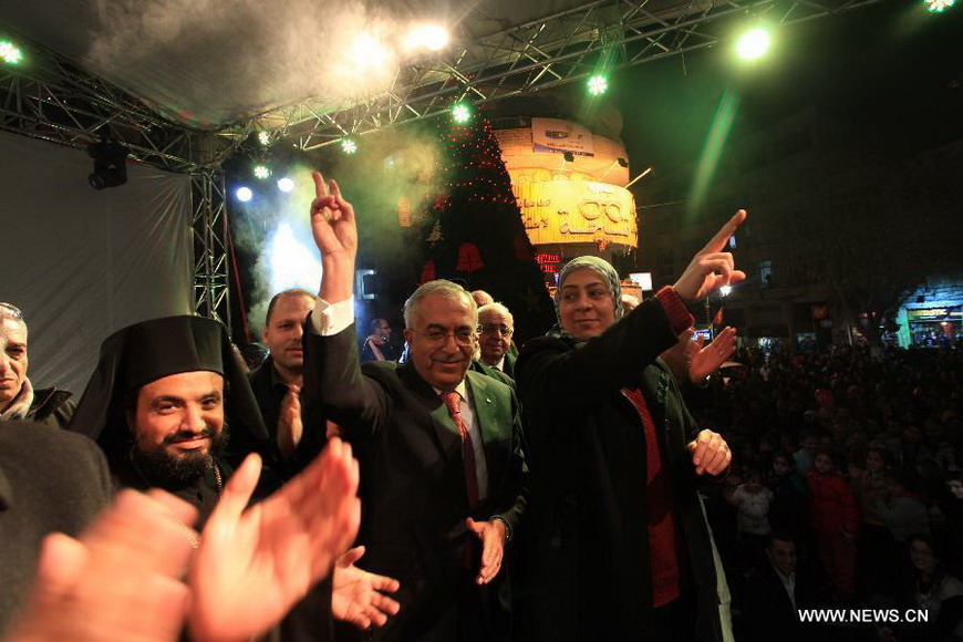 Palestinian Prime Minister Salam Fayyad (2nd R, front) waves as he attends a celebration to inaugurate Christmas' decorations in the West Bank city of Ramallah, on Dec. 12, 2012. (Xinhua/Pool) 