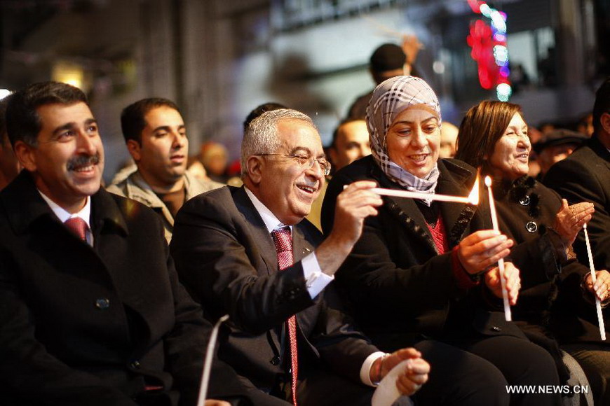 Palestinian Prime Minister Salam Fayyad (2nd L) holds a candle as he attends a celebration to inaugurate Christmas' decorations in the West Bank city of Ramallah, on Dec. 12, 2012. (Xinhua/Fadi Arouri) 