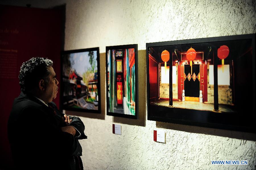 A visitor looks at photos during the "Elegance of Imperial Family, Gongwang Mansion" exhibition in Santiago, capital of Chile, on Dec. 12, 2012. The exhibition presented an opportunity to show the brilliance of Chinese culture through beauty of Chinese architectures and life styles. (Xinhua/Jorge Villegas) 