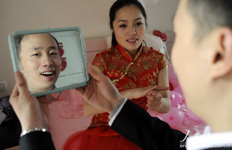 Tian Ye, a deaf-mute, practices hardly the pronunciation "Love" in front of a mirror in Chongqing on March 13, 2012.