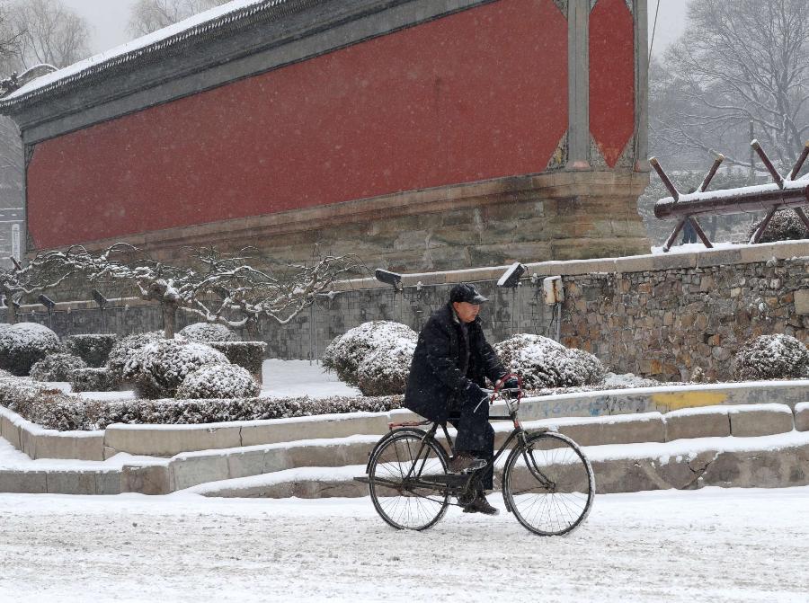 An old man rides bicycle in snow in Chengde, north China's Hebei Province, Dec. 14, 2012. Heavy snow battered parts of northern China these days. (Xinhua/Wang Kun) 