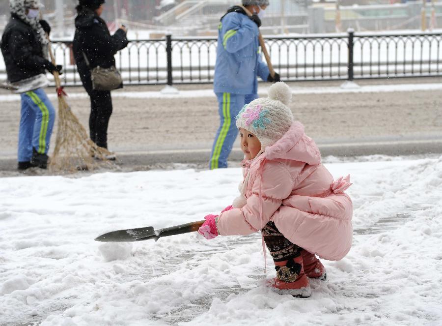 A young girl plays the snow in Chengde City, north China's Hebei Province, Dec. 14, 2012. Heavy snow battered parts of northern China these days. (Xinhua/Wang Kun)