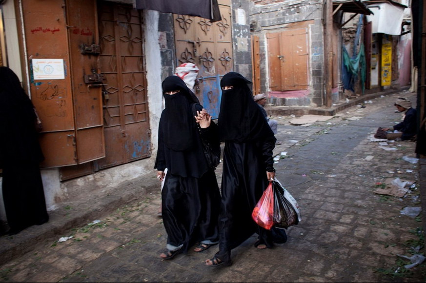 Two women wearing black veils walk past the fairground in Sanaa, Yemen. (Photo/ Global Times)