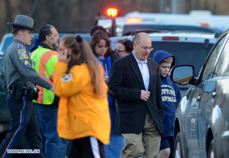 Escorted by his family member, a child (R) leaves the Sandy Hook Elementary School after the fatal school shooting in Newtown, Connecticut, the United States, Dec. 14, 2012. Police in U.S. state Connecticut said Friday that 18 children died on the scene at the school shooting here in Sandy Hook Elementary School, two more died later in the hospital. All together 8 adults were also dead. (Xinhua/Wang Lei) 