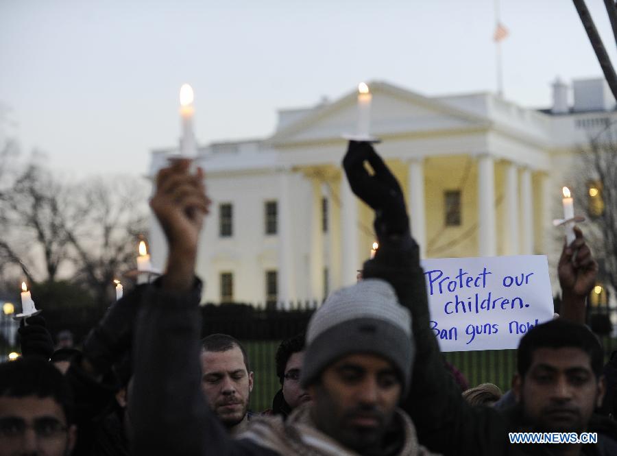 Supporters of gun control legislation hold candles and placards during a rally to pay respect for the shooting victims in front of the White House in Washington, capital of the United States, Dec. 14, 2012, following a deadly shooting spree in an elementary school in Newtown, Connecticut, which took place earlier in the day. (Xinhua/Zhang Jun)