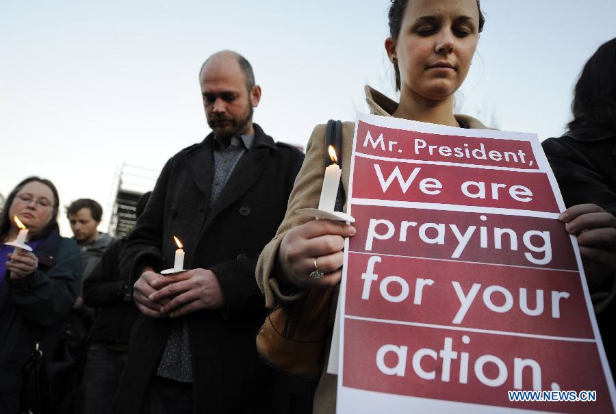 Supporters of gun control legislation hold candles and placards during a rally to pay respect for the shooting victims in front of the White House in Washington, capital of the United States, Dec. 14, 2012, following a deadly shooting spree in an elementary school in Newtown, Connecticut, which took place earlier in the day. (Xinhua/Zhang Jun) 