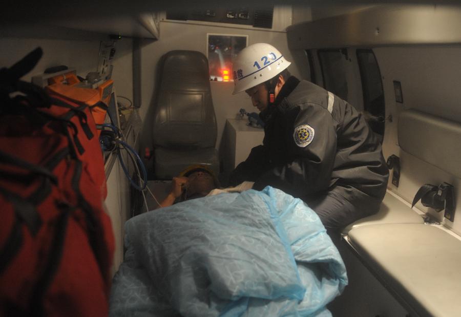 A trapped worker receives treatment on an ambulance at a railway tunnel in Lanzhou, capital of northwest China's Gansu Province, Dec. 14, 2012. Five construction workers who were buried in a tunnel that was under construction around 2:50 p.m. on Wednesday were rescued at 10:07 p.m. Friday. (Xinhua/Nie Jianjiang)  