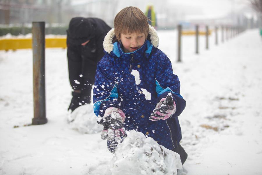 A young boy plays snow in Tianjin, north China, Dec. 14, 2012. Citizens went outdoors to enjoy themselves after heavy snow swept Tianjin on Friday. (Xinhua/Li Xiang)
