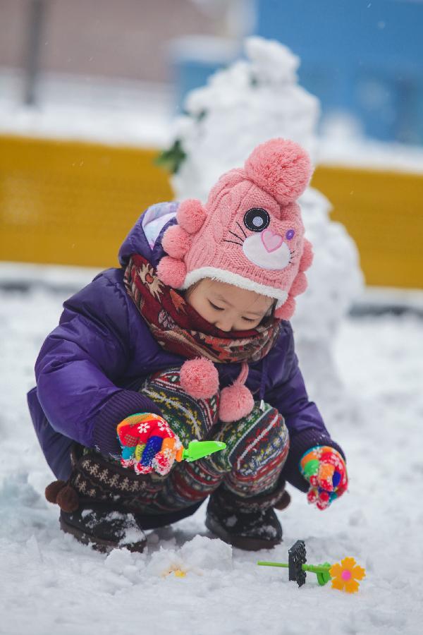 A young girl plays snow in Tianjin, north China, Dec. 14, 2012. Citizens went outdoors to enjoy themselves after heavy snow swept Tianjin on Friday. (Xinhua/Li Xiang)