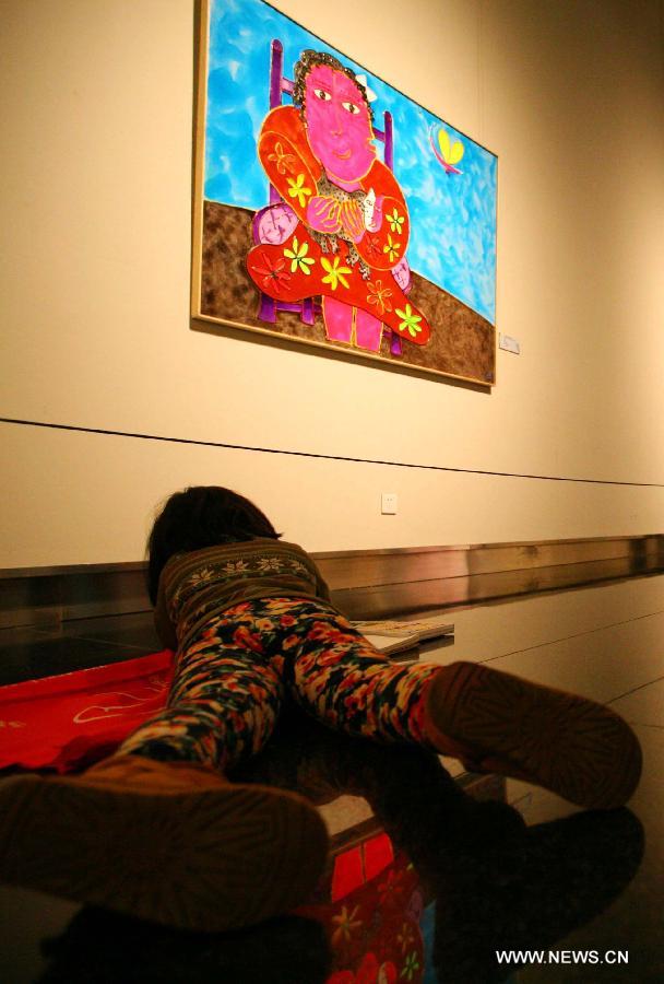 A girl imitates a painting of Juan Ripolles, a well-known Spanish painter and sculptor, at his exhibition "Universe Ripolles" in the Jiangsu Provincial Art Museum in Nanjing, capital of east China's Jiangsu Province, Dec. 16, 2012. A total of 86 artworks of Juan Ripolles were displayed at the exhibition, which kicked off on Tuesday. (Xinhua) 