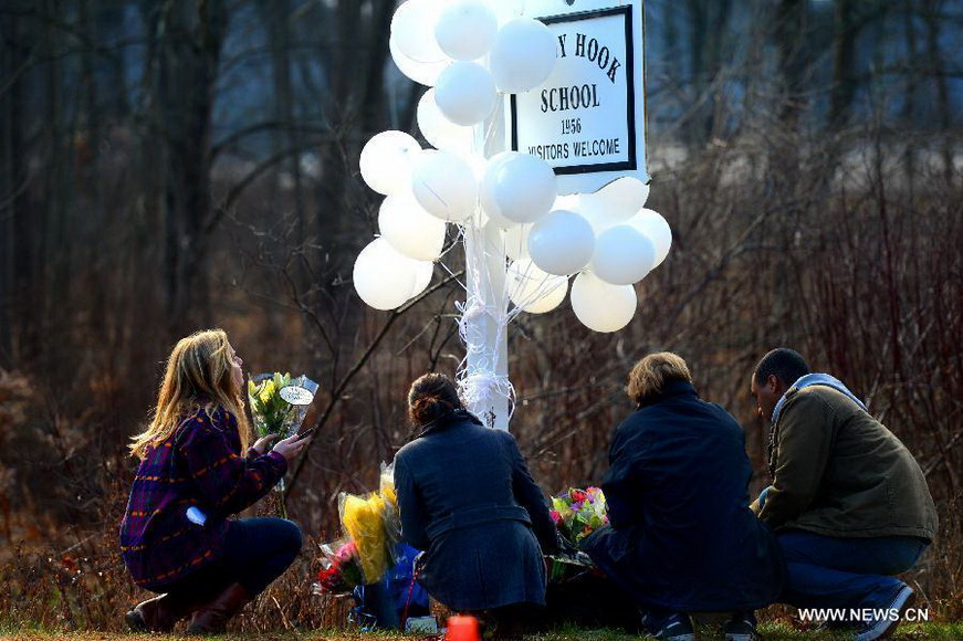 Local residents present flowers near Sandy Hook Elementary School, where a gunman opened fire on school children and staff in Newtown, Connecticut, Dec. 15, 2012. A shooting incident on Friday morning in the elementary school in Newtown of the Connecticut State of the United States killed at least 28 people, including 20 children. (Xinhua/Wang Lei) 