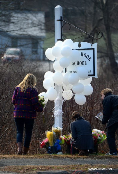 Local residents present flowers near Sandy Hook Elementary School, where a gunman opened fire on school children and staff in Newtown, Connecticut, Dec. 15, 2012. A shooting incident on Friday morning in the elementary school in Newtown of the Connecticut State of the United States killed at least 28 people, including 20 children. (Xinhua/Wang Lei)