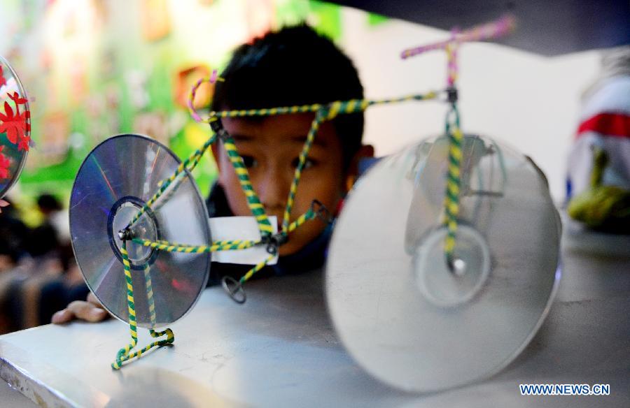 A student views a handicraft made of wastes and scraps during an exhibition in Lanzhou, capital of northwest China's Gansu province, Dec. 14, 2012. A ten-day show themed on environmental protection opened here on Friday, during which over 1,800 artworks made by local primary and middle school students are displayed. (Xinhua/Zhang Meng) 