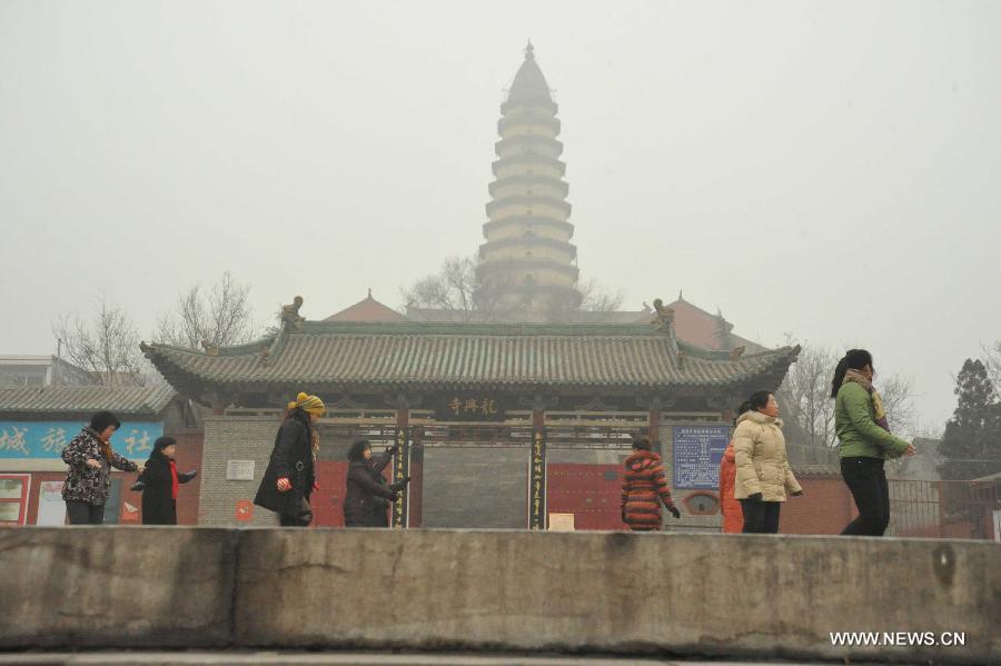 Citizens do exercise before the fog-shrouded Longxing Temple in Xinjiang County of Yuncheng City, north China's Shanxi Province, Dec. 16, 2012. A heavy fog hit Shanxi on Sunday. (Xinhua/Gao Xinsheng)  