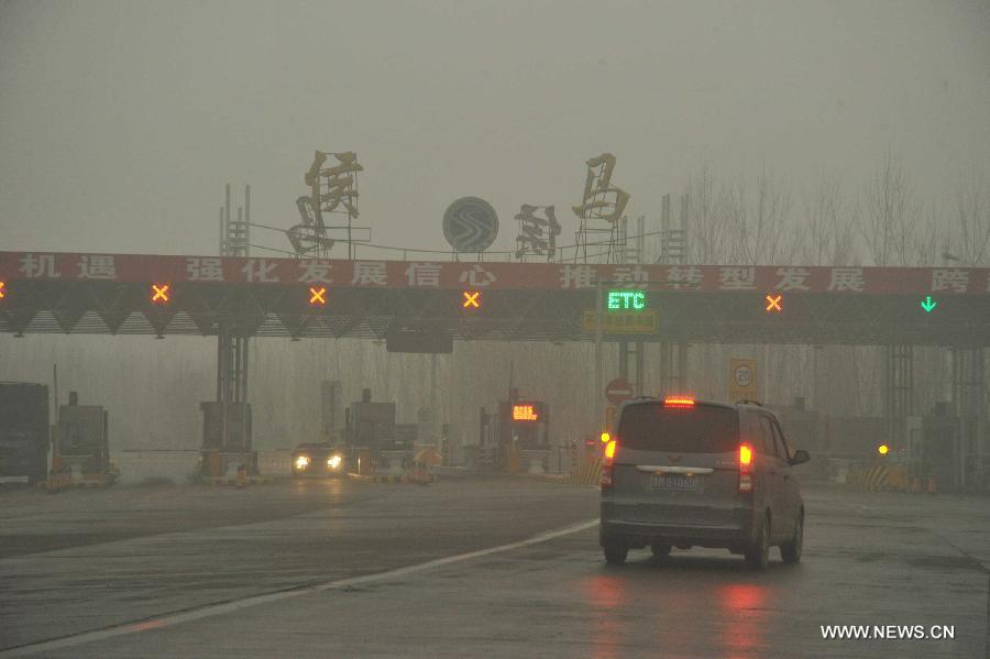 A vehicle moves to the fog-shrouded Houma toll gate in Linfen, north China's Shanxi Province, Dec. 16, 2012. A heavy fog hit Shanxi on Sunday. (Xinhua/Gao Xinsheng)  