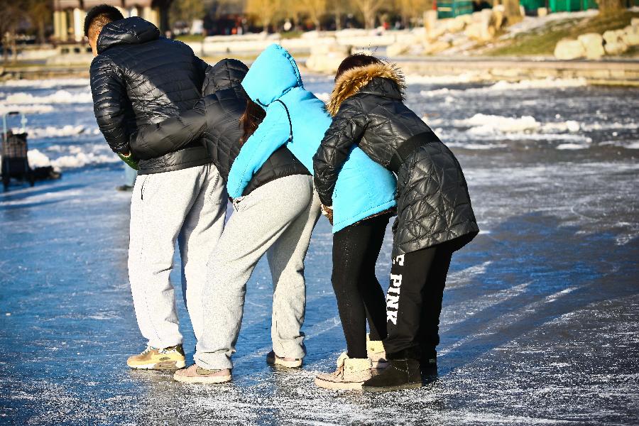 People enjoy themselves upon the ice in Taoranting Park in Beijing, capital of China, Dec. 17, 2012. (Xinhua/Zhang Cheng) 