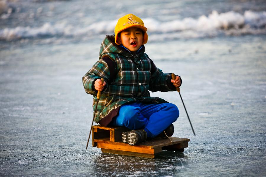 A kid enjoys himself upon the ice in Taoranting Park in Beijing, capital of China, Dec. 17, 2012. (Xinhua/Zhang Cheng) 
