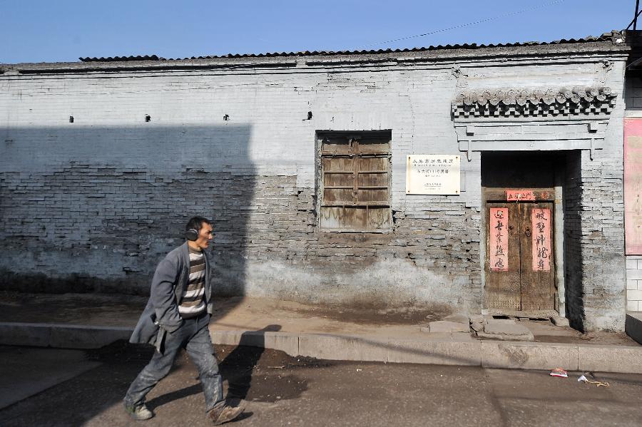 A man walks past a residential house in the Ming Taiyuan County of Jinyuan Town in Taiyuan City, north China's Shanxi Province, Dec. 17, 2012. (Xinhua/Zhan Yan) 