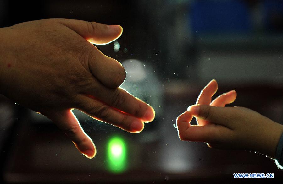 Shen Xiao (L), a hand shadow play artist, performs hand shadow with a student at Ziyan Primary School in Mianzhu, a city in southwest China's Sichuan Province, Dec. 14, 2012. Shen has been teaching students at the primary school every week since last September. (Xinhua/Xue Yubin) 