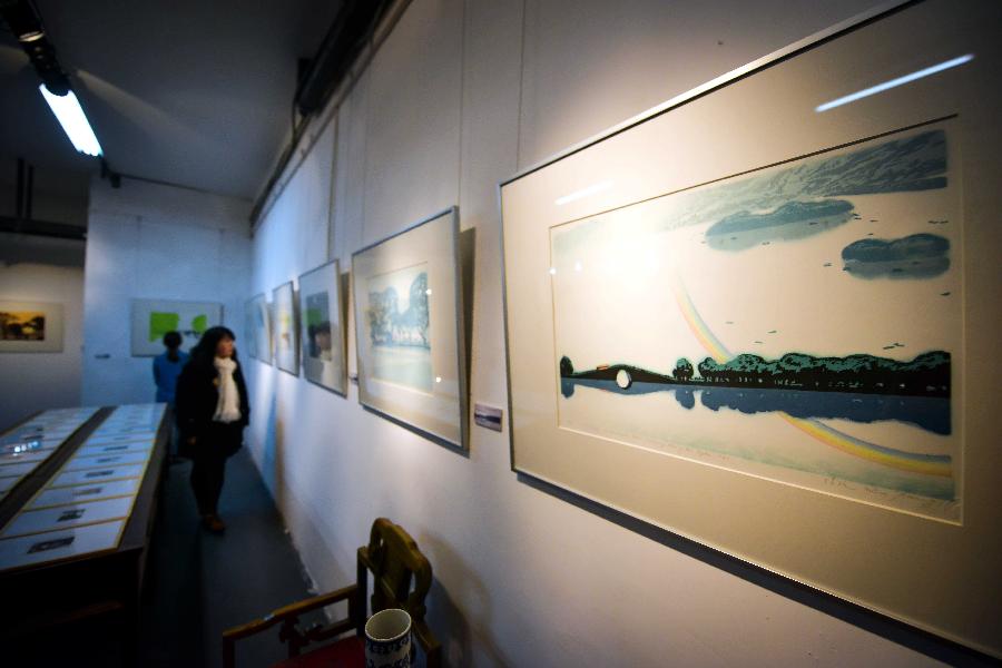 Visitors view woodblock painting works during an exhibition of woodblock paintings depicting the scenery of the West Lake in Hangzhou, capital of east China's Zhejiang Province, Dec. 18, 2012. The technique of woodblock printing was listed as a state intangbile cultural heritage of China in 2008. (Xinhua/Xu Yu) 