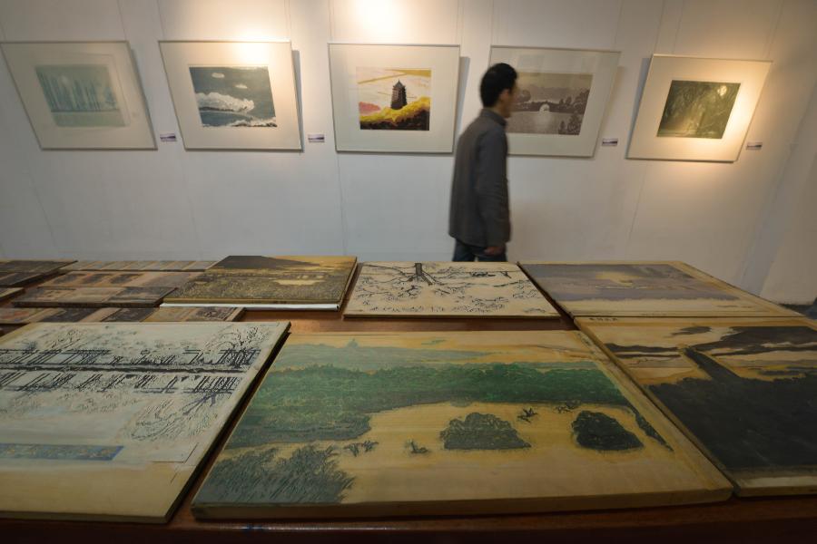 A visitor views woodblock painting works during an exhibition of woodblock paintings depicting the scenery of the West Lake in Hangzhou, capital of east China's Zhejiang Province, Dec. 18, 2012. The technique of woodblock printing was listed as a state intangbile cultural heritage of China in 2008. (Xinhua/Xu Yu) 