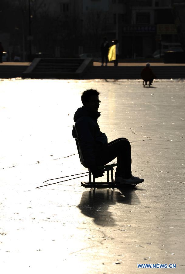 A citizen plays with a sledge on ice on the Beita Lake in Yinchuan, capital of northwest China's Ningxia Hui Autonomous Region, Dec. 18, 2012. (Xinhua/Peng Zhaozhi)