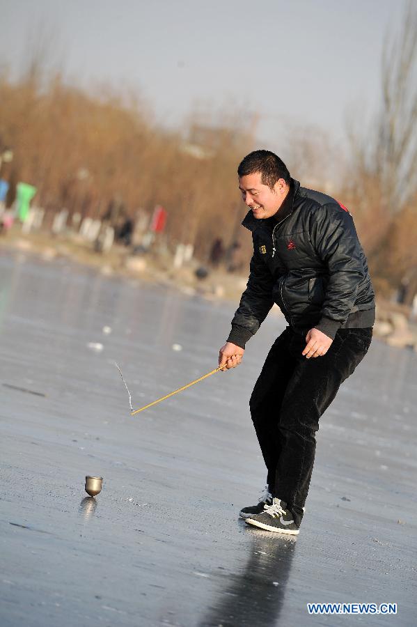 A citizen spins a top on ice on the Beita Lake in Yinchuan, capital of northwest China's Ningxia Hui Autonomous Region, Dec. 18, 2012. (Xinhua/Peng Zhaozhi)