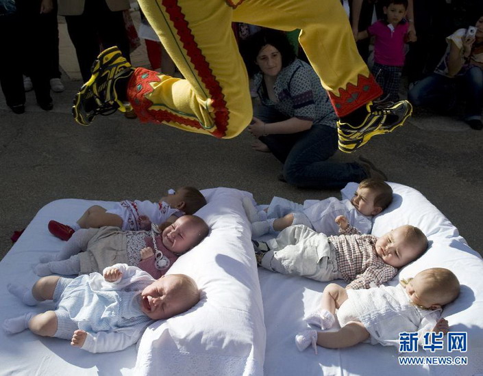 A man dresses up as a devil skips over the babies on the mat during an event in Spain on June 10, 2012. (Xinhua/AFP)
